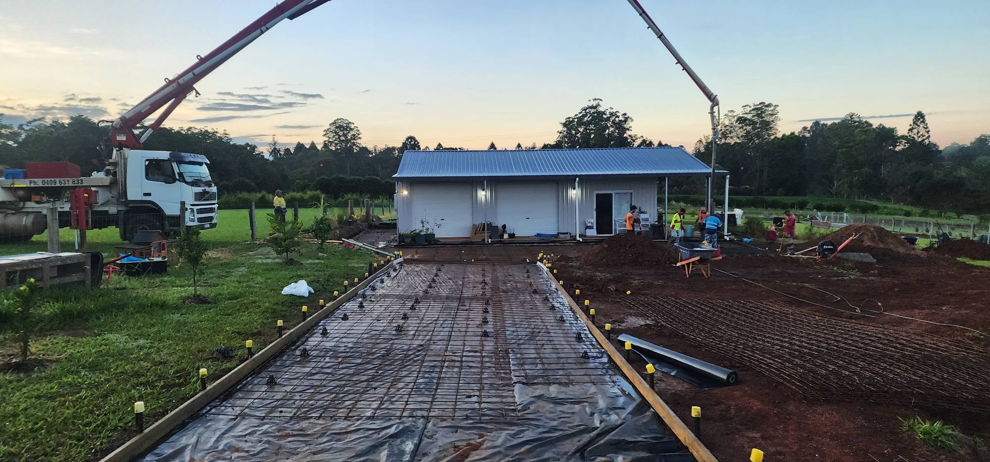 Concreter finishing a freshly poured slab with a steel trowel